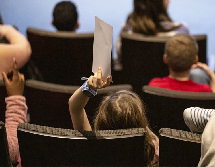 Enfants de camp de jour assis dans un auditorium.