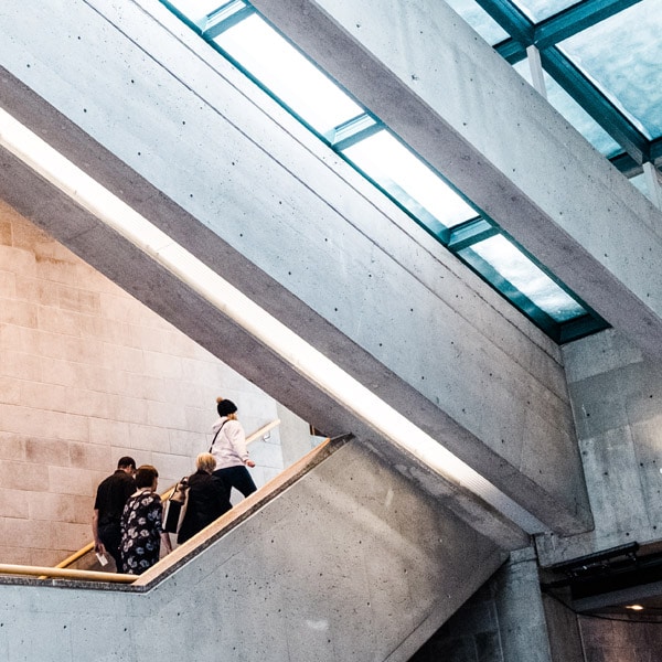 Groupe de visiteurs grimpant les escaliers du hall sous la verrière.