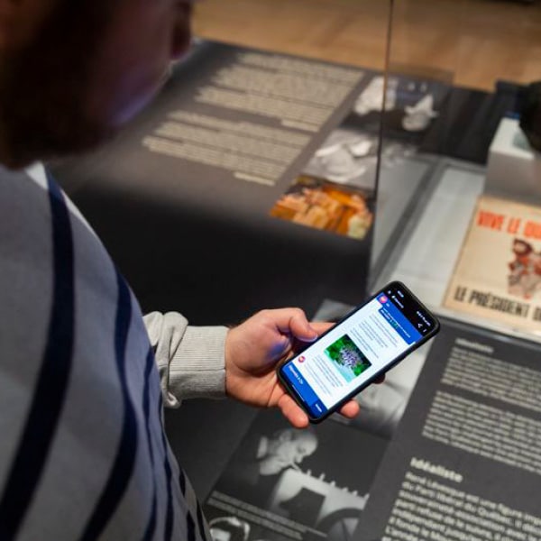 Photo d'un jeune homme en train de communiquer avec l'agent conversationnel de l'exposition René et Lévesque sur ton téléphone mobile